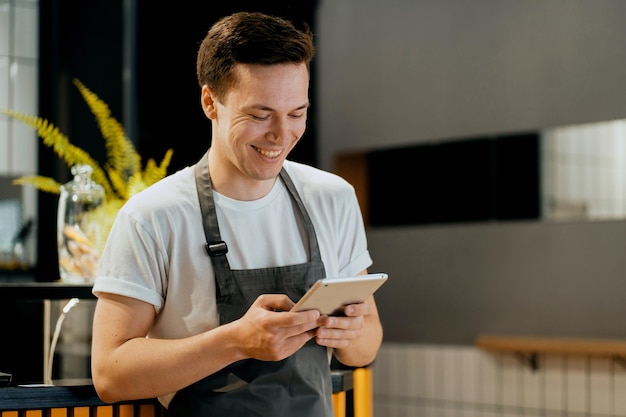 Ele segura um tablet nas mãos e mantém um registro do café no programa online