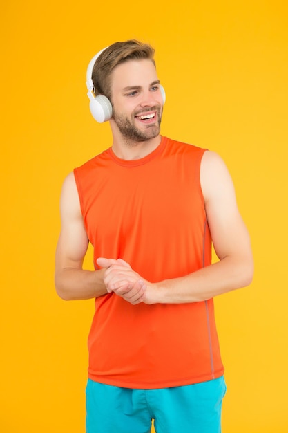 Ele tem um ótimo estilo. cara desportista com fones de ouvido estéreo. moda de fitness masculino. homem no fone de ouvido ouve música para treinamento. esporte e música. qualidade de som. dispositivo sem fio inovador. treino.