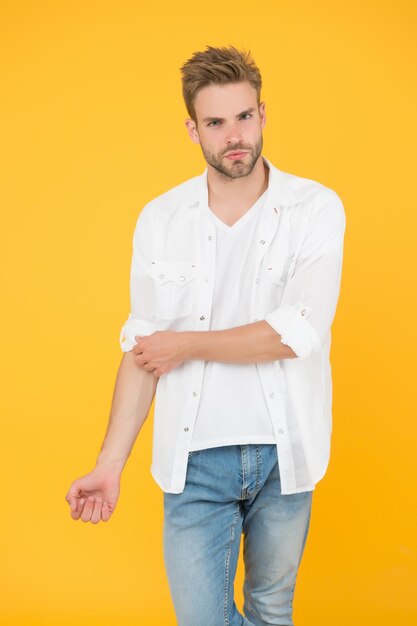 Ele tem um ótimo estilo. retrato do homem milenar em roupas casuais. homem bonito usa camiseta branca e posando no estúdio. casualmente bonito. estilo de vida urbano casual. empresário em jeans e camisa.