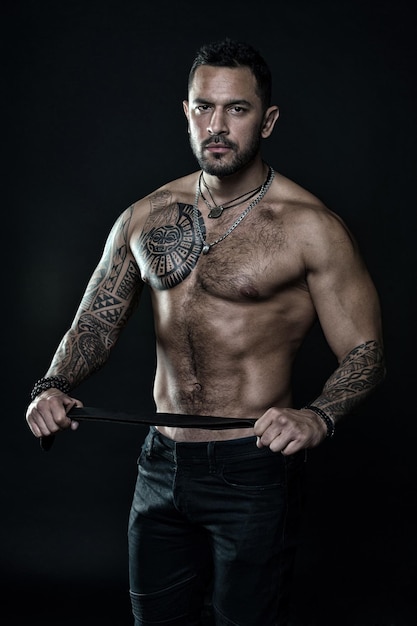 Ele tem um torso perfeito homem musculoso segura cinto de couro fetiche bdsm jogo de amor Esportista peito e barriga nus Esporte e fitness Masculinidade e brutalidade bonito fisiculturista Rocker ou punk