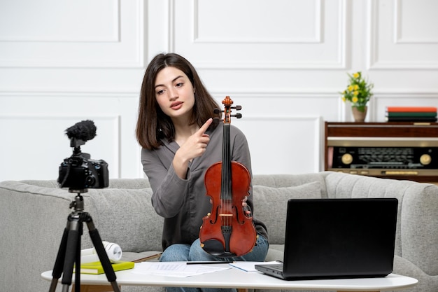 Elearning de forma remota en casa dando clases de violín joven linda hermosa niña explicando en cámara