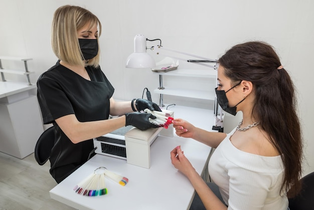 Elección del color de las uñas Una niña elige el color de sus uñas en un salón de belleza Belleza y salud de las uñas Manicura y cliente en un salón de belleza