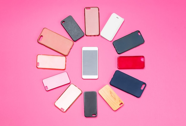 Elección de cubiertas traseras de plástico multicolor para teléfonos móviles sobre fondo rosa con un teléfono inteligente en el lateral