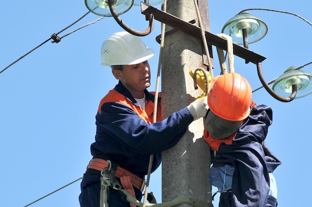 Un electricista ayuda al trabajador afectado por una descarga eléctrica. Entrenamiento en un maniquí.