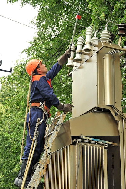 El electricista controla el voltaje en la línea de transmisión de energía antes de reparar la subestación