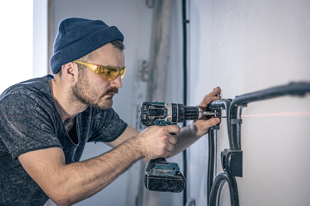 Un electricista está montando enchufes eléctricos en la pared blanca en el interior