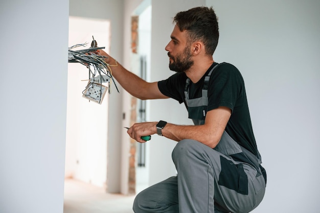 El electricista está trabajando con cables en el interior de la habitación