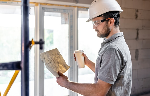 Foto un electricista está estudiando un dibujo de construcción con un café en la mano.