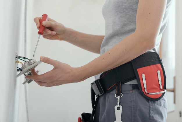 Electricista femenina arreglando un enchufe en casa