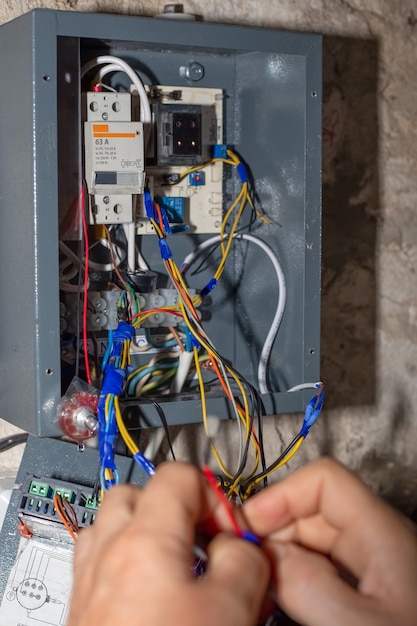 Foto un electricista instala cables en una caldera eléctrica para calentar la casa.