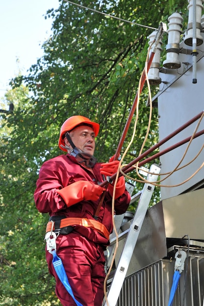 El electricista instala la tierra en la línea eléctrica antes de reparar la subestación