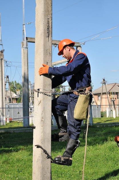 Electricista levantándose sobre un pilar de hormigón para reparar la línea eléctrica