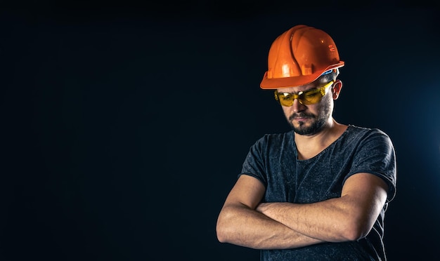 Electricista masculino en un casco protector con gafas sobre un fondo negro