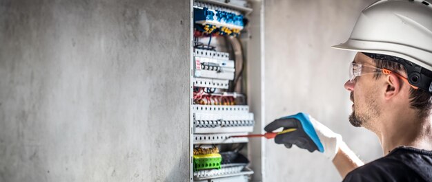 Electricista masculino que trabaja en la central eléctrica con cable de conexión eléctrica