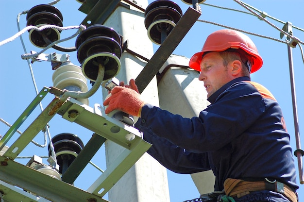 Un electricista en un poste eléctrico cambia un aislante dañado