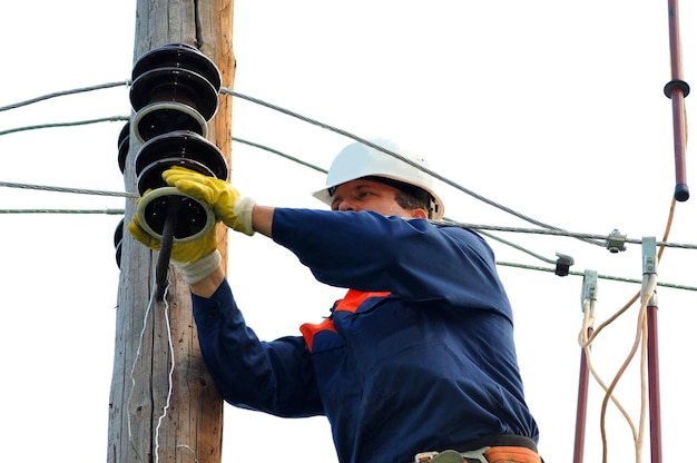 Un electricista en un poste eléctrico cambia un aislante dañado