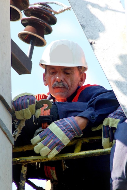 Un electricista en un poste eléctrico cambia un aislante dañado