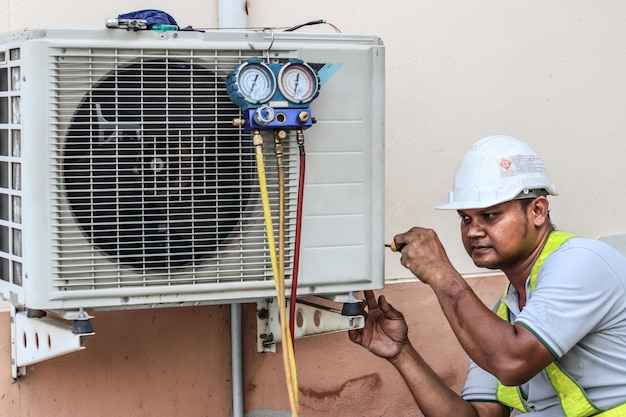 Un electricista profesional está arreglando un acondicionador de aire pesado El modelo es un reparador electricista Reparación de aire acondicionado