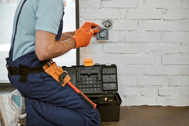 Foto electricista reparar toma de corriente eléctrica con destornillador