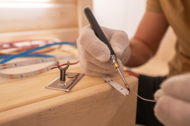 Electricista con soldador que fija el cable de rayas LED