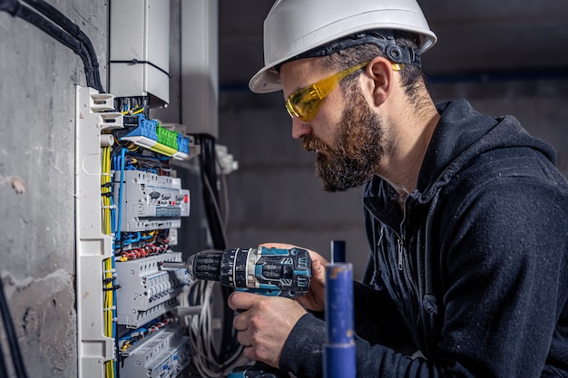 Foto un electricista trabaja en una centralita con un cable de conexión eléctrica.