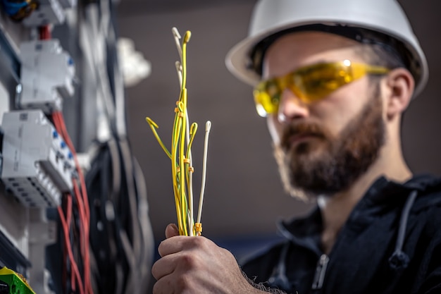 Un electricista trabaja en una centralita con un cable de conexión eléctrica.