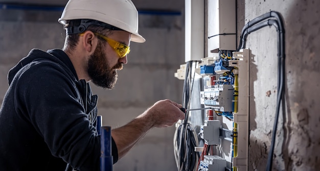 Un electricista trabaja en una centralita con un cable de conexión eléctrica.