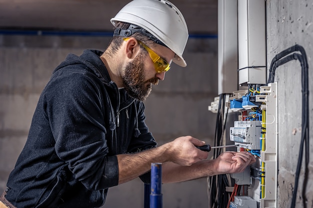 Un electricista trabaja en una centralita con un cable de conexión eléctrica.