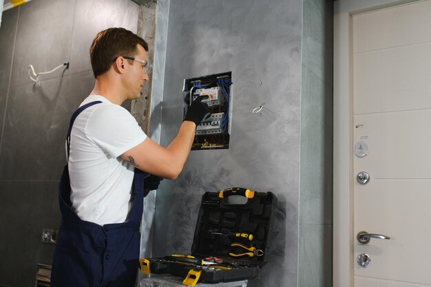 Un electricista trabaja en una centralita con un cable de conexión eléctrica.