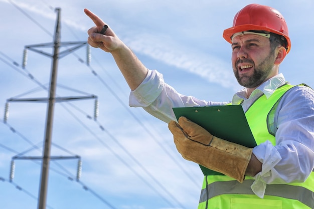 Electricista trabajando en un casco con guantes de pie en un campo