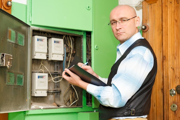 Electricista en el trabajo inspeccionando la conexión del cableado de la línea eléctrica de alta tensión en el cuadro de fusibles de distribución