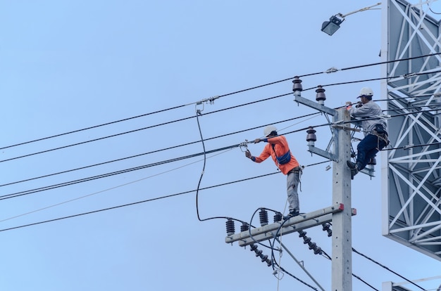 Los electricistas se suben a postes eléctricos para instalar y reparar líneas eléctricas.