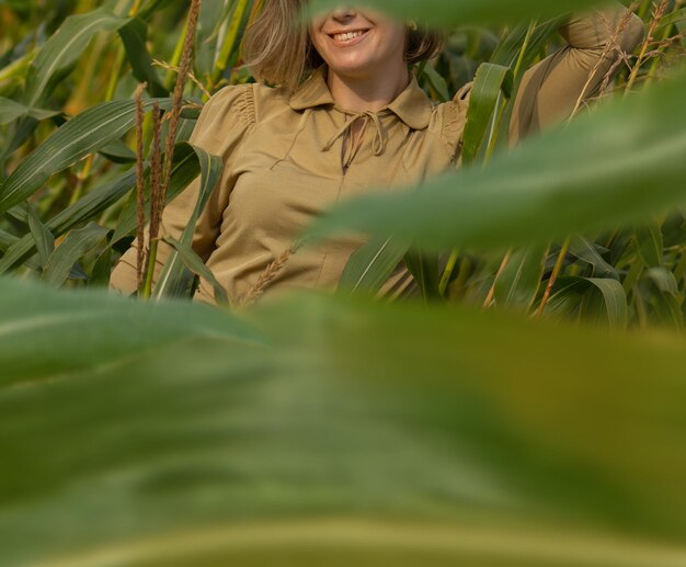 Elegança e moda na temporada de verão ao ar livre Bela jovem em um vestido dourado em uma plantação de milho verde