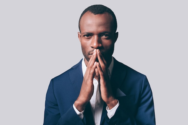 Elegância e masculinidade. Retrato de um jovem africano pensativo em uma jaqueta casual elegante, segurando a mão perto do rosto e olhando para a câmera em pé