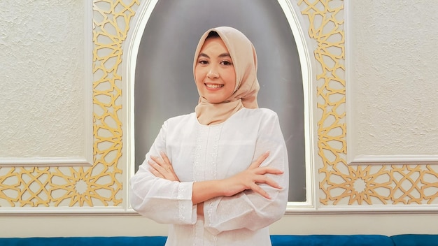 La elegancia de una mujer indonesia con un hijab una expresión de sonrisa feliz brazos cruzados con una I