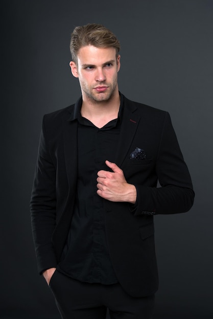 Elegancia en sencillez. Tendencia de la moda negra. Gerente elegante hombre usar traje formal negro sobre fondo oscuro. Razones por las que el negro es el único color que vale la pena usar. Reglas para usar toda la ropa negra.