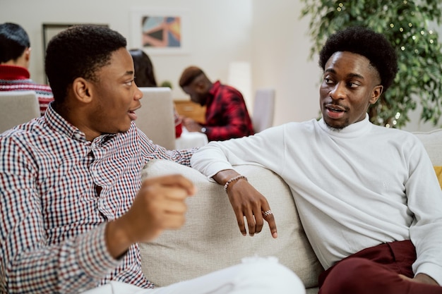 Elegant gekleidete Cousin-Brüder-Freunde sitzen auf der Couch und sprechen gestikulierende Männer