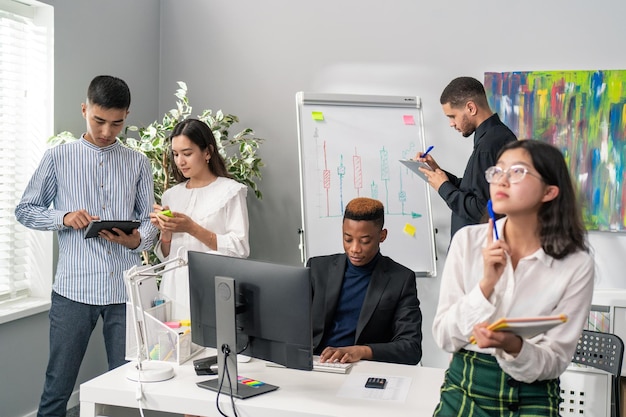 Elegant gekleidete Mitarbeiter sitzen nachmittags im Firmenbüro und suchen gemeinsam nach Ideen