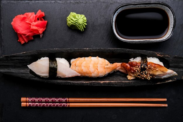 Elegant servierte Sushi-Set-Komposition mit frischen Garnelen und rohem Lachs auf schwarzem Teller mit Ingwer...