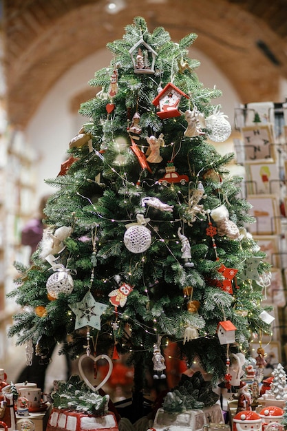 Elegante árbol de navidad con adornos y juguetes en escaparate de la tienda por la noche Decoración navideña moderna en la calle de la ciudad Vacaciones de invierno atmosféricas en Europa Feliz Navidad y Felices Fiestas