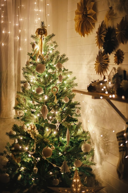 Elegante árbol de Navidad decorado con adornos boho y luces doradas en una habitación atmosférica