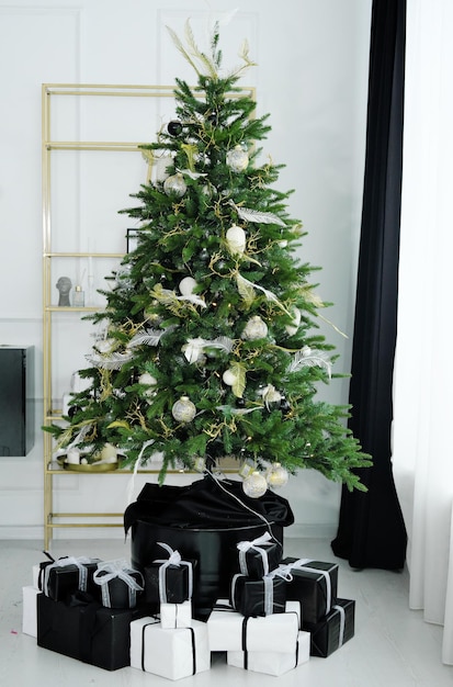 Un elegante árbol de Navidad se encuentra en la sala de estar Regalos en blanco y negro debajo del árbol de Navidad