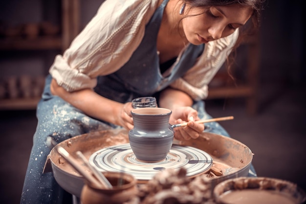 Foto elegante artesão de oleiro mostra como trabalhar com argila e roda de oleiro. produtos artesanais.