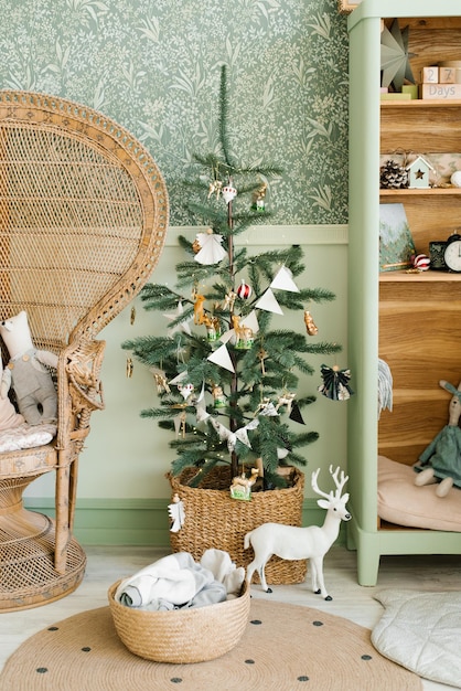Elegante árvore de Natal escandinava com brinquedos e bandeiras na decoração interior do quarto das crianças