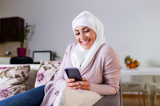 Elegante y atractiva mujer musulmana que usa un teléfono inteligente móvil buscando información en línea