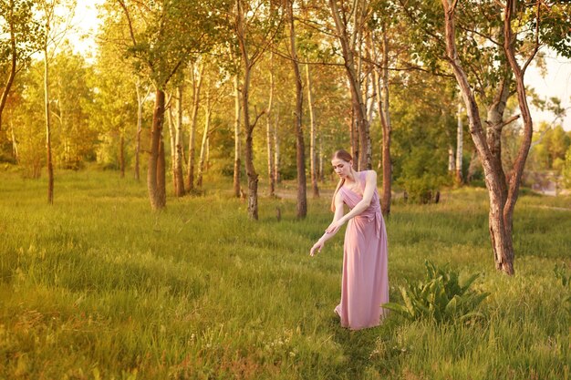 Una elegante bailarina en la naturaleza en un bosque al atardecer en la postal de verano Banner