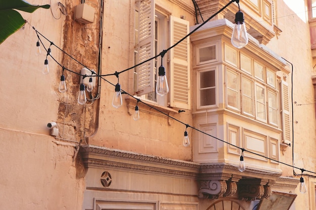 Elegante balcón de madera envejecido y ventana con sombras en un antiguo edificio residencial en el centro de La Valeta, Malta