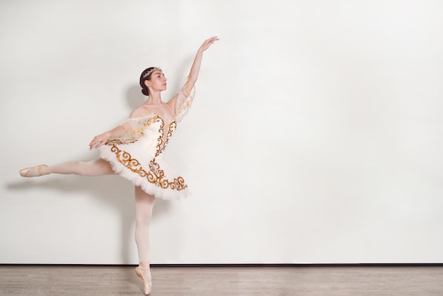 Elegante Ballerina führt Ballettübungen im Studio vor weißem Hintergrund durch