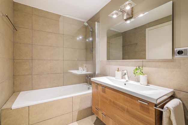 Este elegante baño cuenta con un diseño moderno con azulejos de color beige, una amplia ducha, un elegante lavabo y