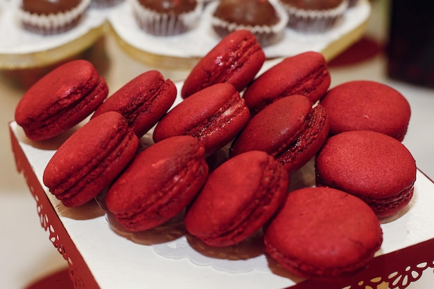 Elegante bar de caramelos de macarrones rojos con dulces en la recepción de bodas de lujo en el restaurante cupcakes macarons en el espacio de la mesa para texto